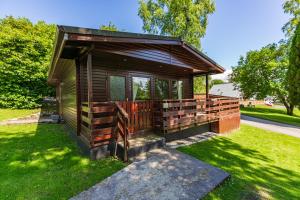 a small wooden cabin in a field of grass at Bluebell Lodge 2 with Hot Tub in Newton Stewart