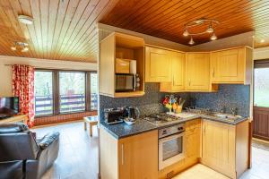 uma cozinha com armários de madeira e uma bancada em Bluebell Lodge 2 with Hot Tub em Newton Stewart