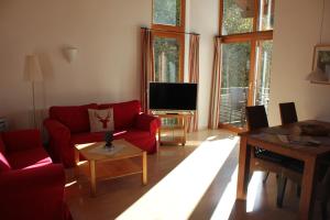 オーバーアマガウにあるFerienwohnungen Almrauschのリビングルーム(赤いソファ、テレビ付)