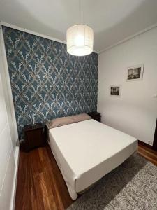 um quarto com uma cama branca e uma parede em Precioso apartamento a estrenar en Bilbao. em Bilbao
