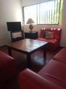 sala de estar con mesa de madera y sillas rojas en Amplio departamento en Godoy cruz en Godoy Cruz