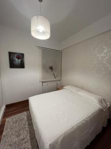 um quarto com uma cama branca e uma parede branca em Precioso apartamento a estrenar en Bilbao. em Bilbao