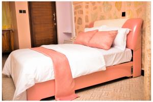an orange bed with white sheets and orange pillows at Ruby Haven in Kampala