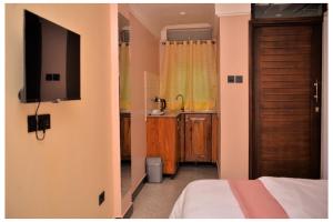 a room with a bed and a tv and a kitchen at Ruby Haven in Kampala