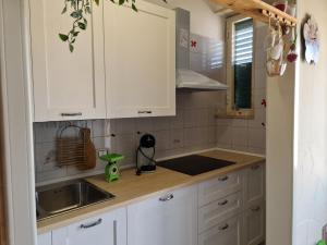 uma cozinha com armários brancos e um lavatório em B&B DANIELA em Leporano Marina