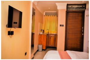 a bedroom with a bed and a television on a wall at Ruby Haven in Kampala