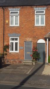 a brick house with two garage doors and flowers at Cottage 5 minutes walk to river and town centre in Stratford-upon-Avon