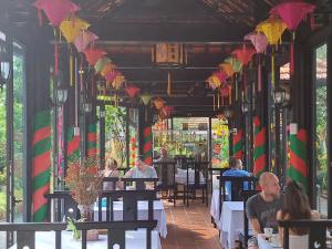 un grupo de personas sentadas en mesas en un restaurante en Betel Garden Villa, en Hoi An