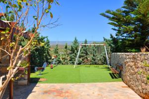 a garden with a swing set on the grass at Lagos Studios & Apartments in Palekastron