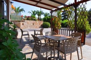 a patio with tables and chairs under a pergola at Lagos Studios & Apartments in Palekastron