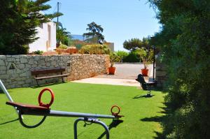a yard with two chairs and a stone wall at Lagos Studios & Apartments in Palekastron