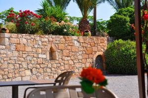 a stone wall with a table and chairs and flowers at Lagos Studios & Apartments in Palekastron