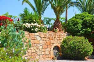 a garden with flowers and plants on a stone wall at Lagos Studios & Apartments in Palekastron
