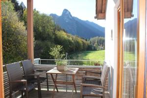 a balcony with a table and chairs and a view of a river at Ferienwohnungen Almrausch in Oberammergau