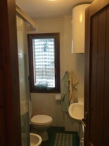 a bathroom with a toilet and a sink and a window at Cozy mountains apartments in Borgata Sestriere