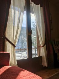 a bedroom with a window with a view of a snow covered yard at Cozy mountains apartments in Borgata Sestriere