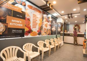 a row of chairs in a restaurant with a woman standing at HOTEL BOOPATHI Madurai in Madurai