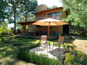 a patio with chairs and an umbrella in front of a house at Cabañas Walddorf - Alcatraz in Atemajac de Brizuela
