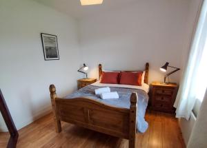 1 dormitorio con 1 cama de madera y 2 lámparas en Cosy Cottage by the Sea en Galway