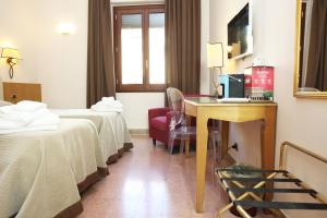 a hotel room with two beds and a desk at Albergo Russo in Trapani