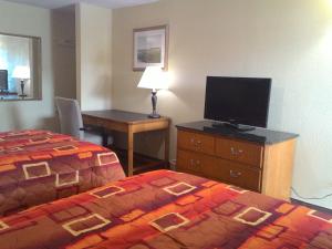 Habitación de hotel con cama y escritorio con TV. en Apalachicola Bay Inn, en Apalachicola
