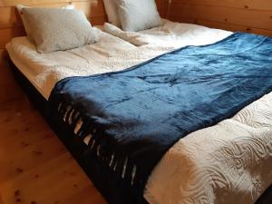 a bed with a blue blanket on top of it at Fröya Timber Cottage in Arvika