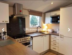 a kitchen with white cabinets and a stove at Susie's Beautiful Caravan near the sea in Pwllheli