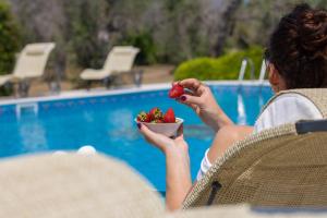 a woman sitting in a chair holding a bowl of strawberries at Casa Ulmi con piscina in Uggiano la Chiesa