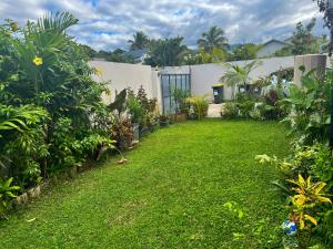 a backyard with a yard of grass and plants at Villa Mary Guest House in Saint-André