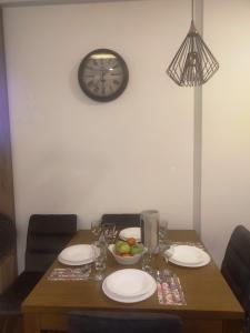 einen Tisch mit Tellern, eine Schale Obst und eine Uhr in der Unterkunft NLux46 Milmari in Kopaonik