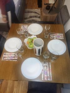 einem Holztisch mit weißen Tellern und Gläsern darauf in der Unterkunft NLux46 Milmari in Kopaonik