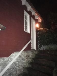 a red house with a white door and stairs at night at Fischerhaus am Blankeneser Elbhang in Hamburg