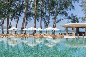 a swimming pool with chairs and umbrellas at InterContinental Phuket Resort by IHG in Kamala Beach