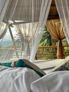 a bed with white curtains and a view of the mountains at Tabatinga, Hermosa Cabaña Privada en Reserva Natural - Cali Valle del Cauca in Cali