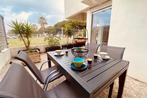 a wooden table and chairs on a balcony with a table at Escapade au Soleil B002 in Le Grau-du-Roi