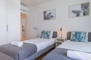 a bedroom with two beds and a table with a lamp at Campolide 2 bedroom delight By Innkeeper in Lisbon