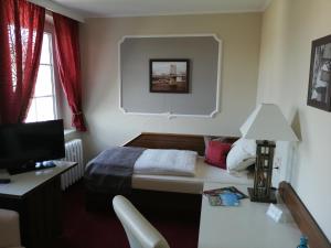 a bedroom with a bed and a desk with a television at Hotel Weiße Taube in Döbeln