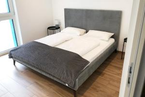een groot bed met een grijs hoofdeinde in een slaapkamer bij Laurentia Penthouse-Apartment in Merano