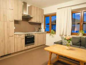cocina con armarios de madera, mesa y sofá en Ferienwohnungen Ebensperger - Chiemgau Karte en Inzell