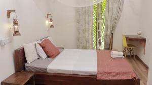 a bedroom with a bed with a desk and a window at Cafe Central in Ilha de Moçambique