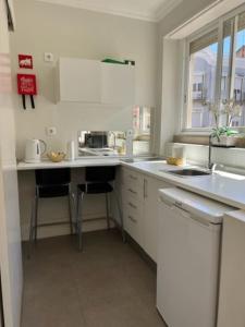a white kitchen with a sink and a counter at Romantic and Bright Studio Apartment in Arroios - SSL 2B in Lisbon