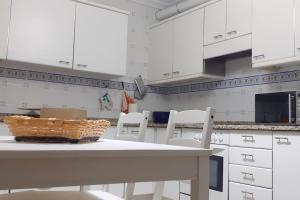 cocina con armarios blancos, mesa y sillas en Casa SAN MIGUEL en Tarazona, en Tarazona de Aragón