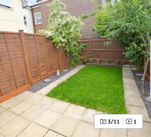 a backyard with a fence and green grass at Cosy 2 Bedroom House in Dunstable