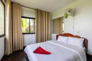 um quarto com uma cama com uma toalha vermelha em Damnak Phnom Krom Homestay em Phumĭ Rœssei Lŭk