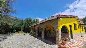 un pequeño edificio amarillo con un patio de ladrillo en El Rancho, en Nobsa