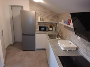 a small kitchen with a refrigerator and a sink at Apartman Vidas in Rab