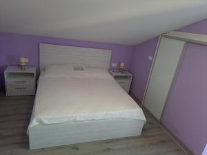 a bedroom with a white bed and purple walls at Apartman Vidas in Rab