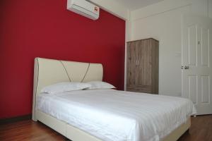 a bedroom with a white bed with a red wall at Likas House @ Alawa Homes in Kota Kinabalu