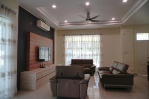 a living room with leather furniture and a flat screen tv at Likas House @ Alawa Homes in Kota Kinabalu