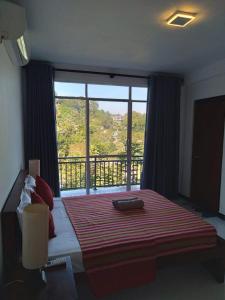 a bedroom with a bed with a large window at Cozy Homestay Kandy in Kandy